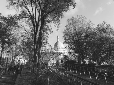 Vista em preto e branco da Basílica de Sacré-Cœur entre árvores, em Montmartre, Paris.