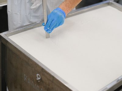 Trabalhador utiliza uma ferramenta durante a produção de queijo em uma unidade de laticínios.