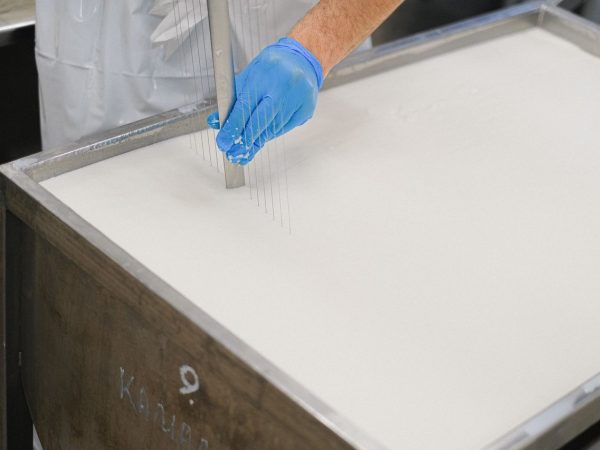 Trabalhador utiliza uma ferramenta durante a produção de queijo em uma unidade de laticínios.