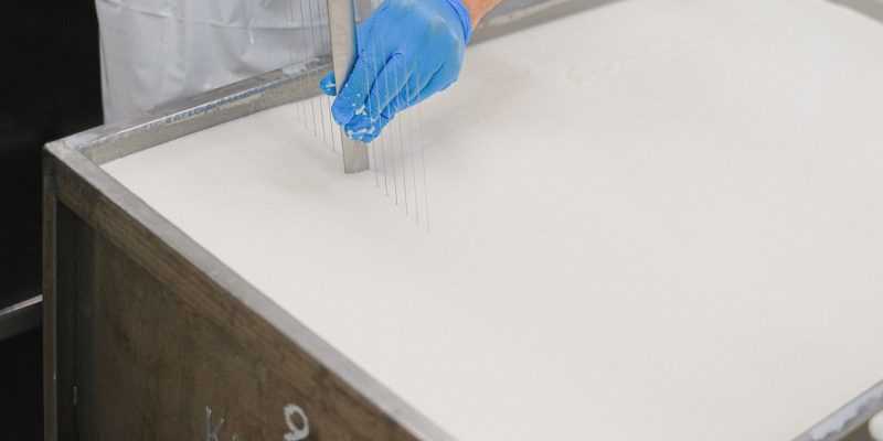 Trabalhador utiliza uma ferramenta durante a produção de queijo em uma unidade de laticínios.