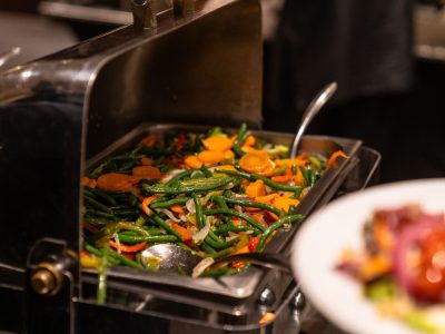 Travessa de buffet com variedade de vegetais preparados, pronta para ser servida.