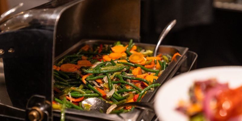 Travessa de buffet com variedade de vegetais preparados, pronta para ser servida.