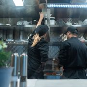 Dois chefs trabalham juntos no preparo de alimentos em uma cozinha profissional.