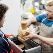 Funcionário de cozinha coloca recipientes de comida em uma bolsa para entrega.