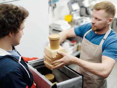 Funcionário de cozinha coloca recipientes de comida em uma bolsa para entrega.