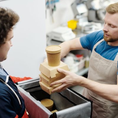 Funcionário de cozinha coloca recipientes de comida em uma bolsa para entrega.