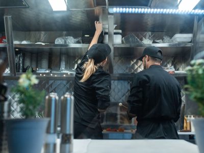 Dois chefs trabalham juntos no preparo de alimentos em uma cozinha profissional.