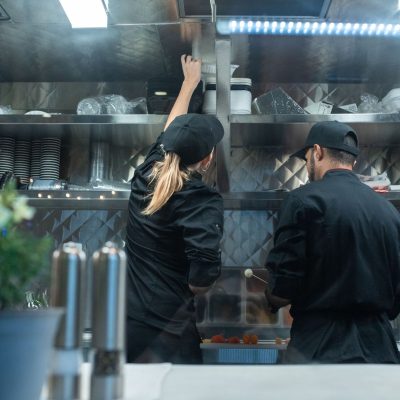 Dois chefs trabalham juntos no preparo de alimentos em uma cozinha profissional.