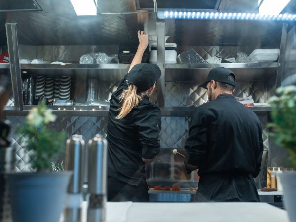 Dois chefs trabalham juntos no preparo de alimentos em uma cozinha profissional.